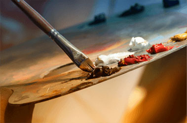 Photo: A paintbursh dipping into paints on a palette